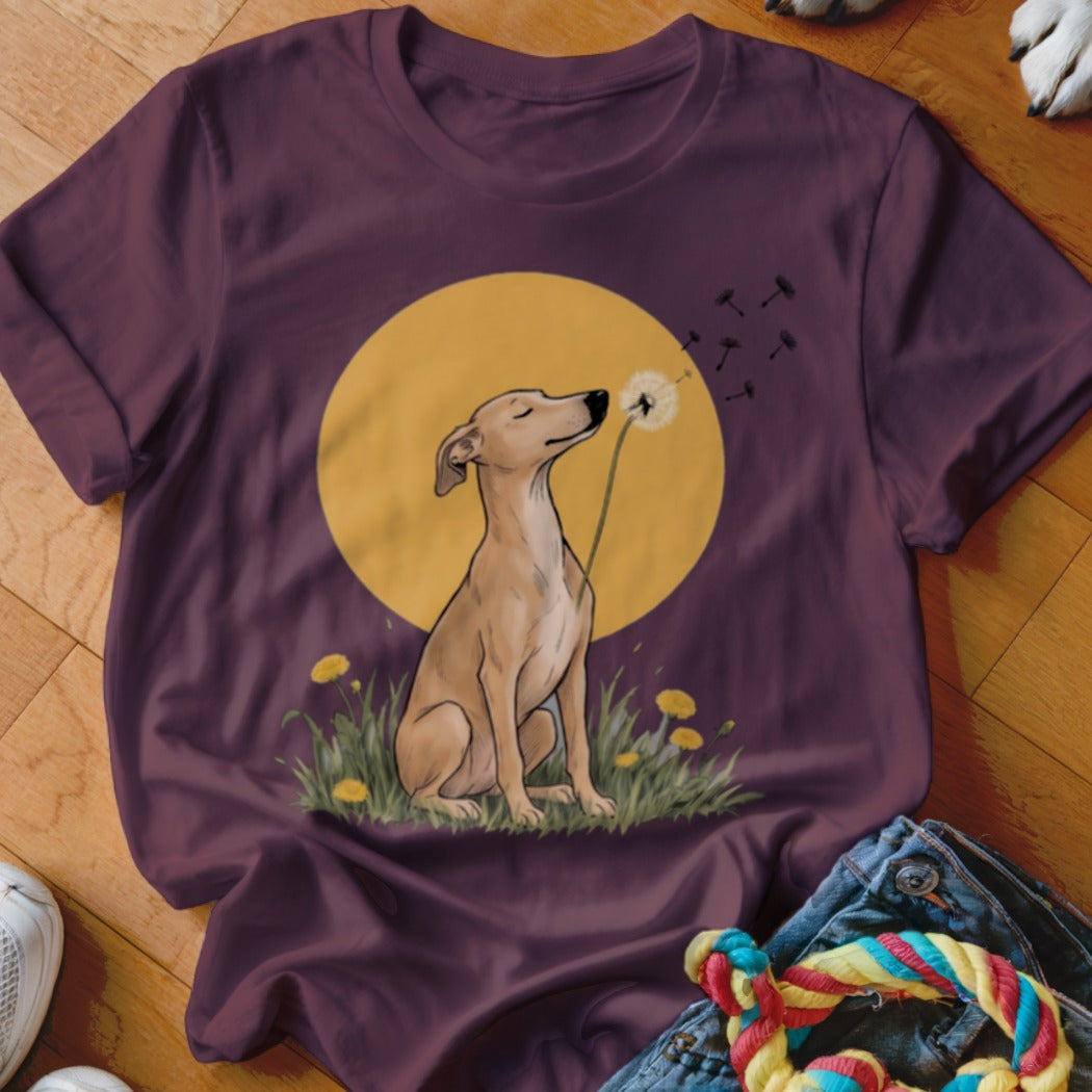 A dark purple t-shirt features a graphic of a dog blowing dandelion seeds against a yellow circle.