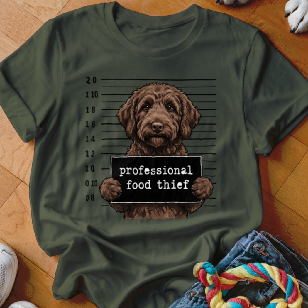 Brown dog mugshot with "professional food thief" sign on a green t-shirt.
