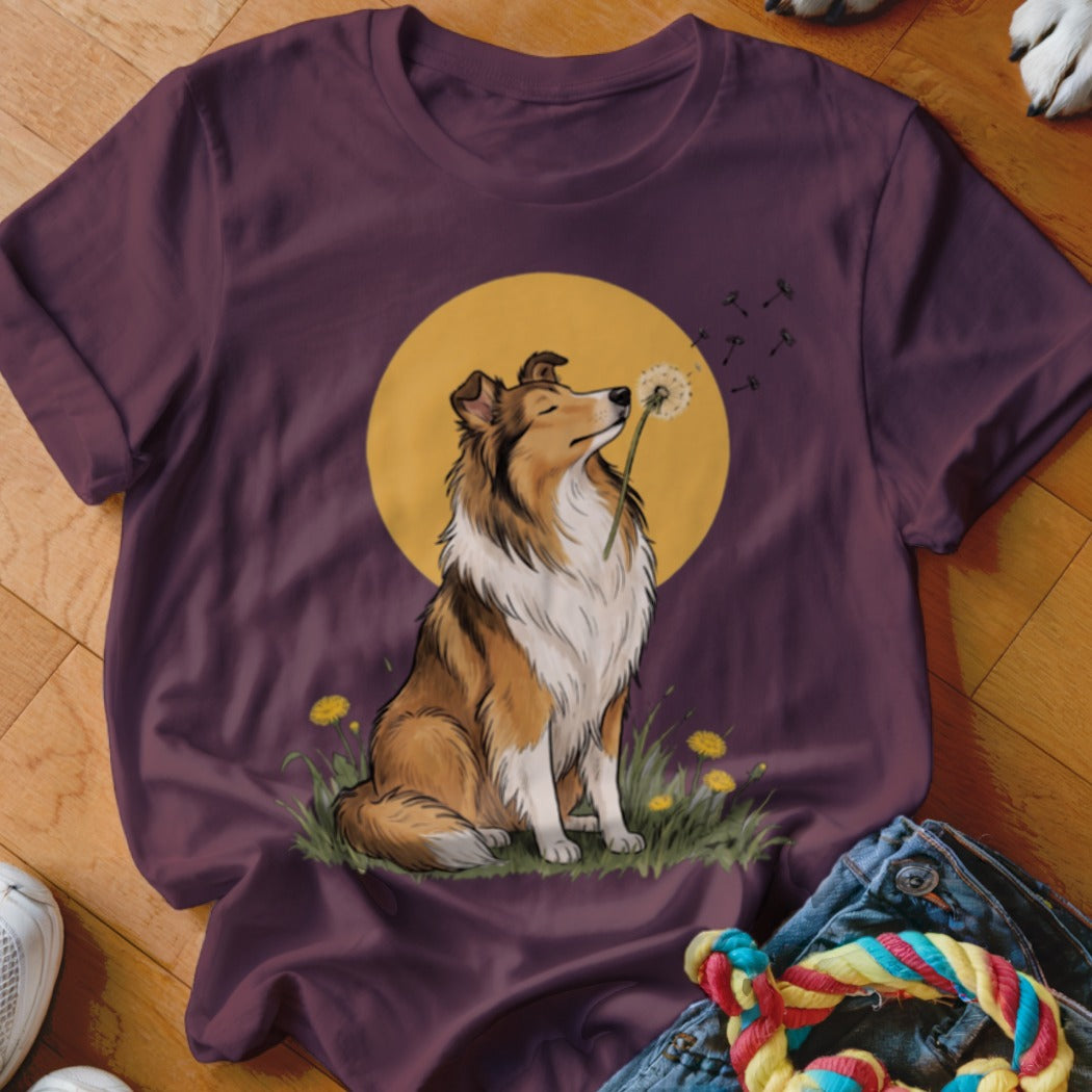 Plum t-shirt featuring an illustrated Rough Collie sitting in grass and blowing a dandelion against a yellow sun.