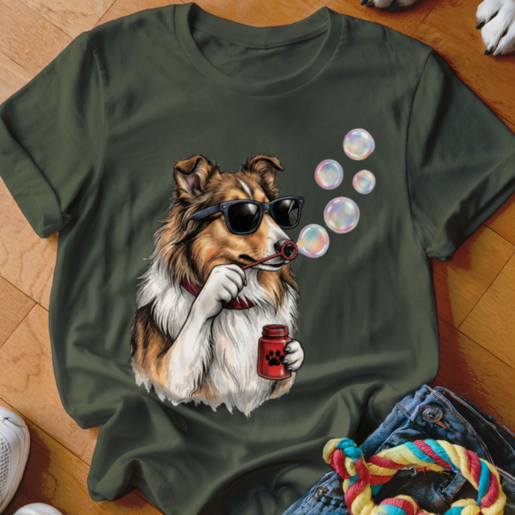 An olive green t-shirt features a graphic of a Sheltie dog wearing sunglasses and blowing bubbles.