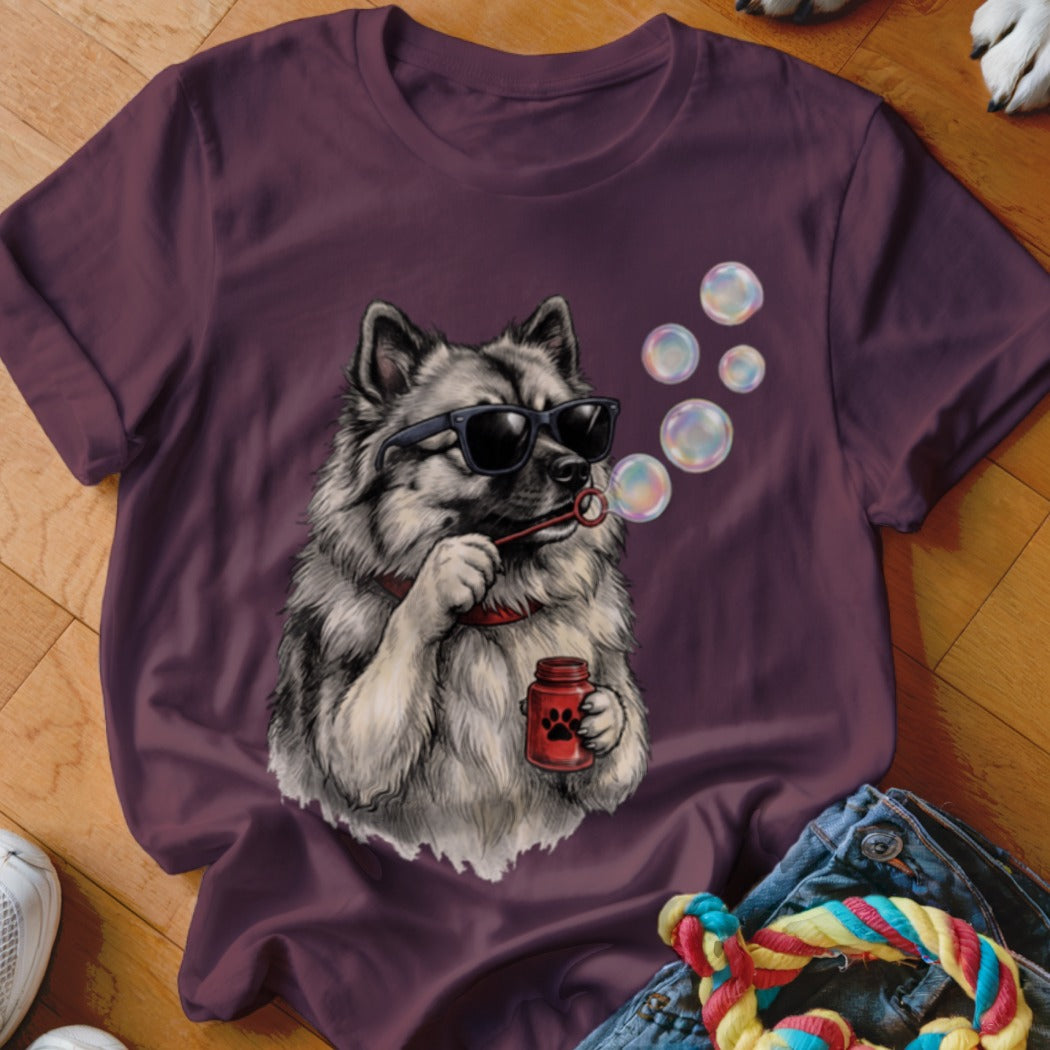 A dark purple crewneck t-shirt featuring a graphic of a fluffy dog wearing sunglasses and blowing bubbles.