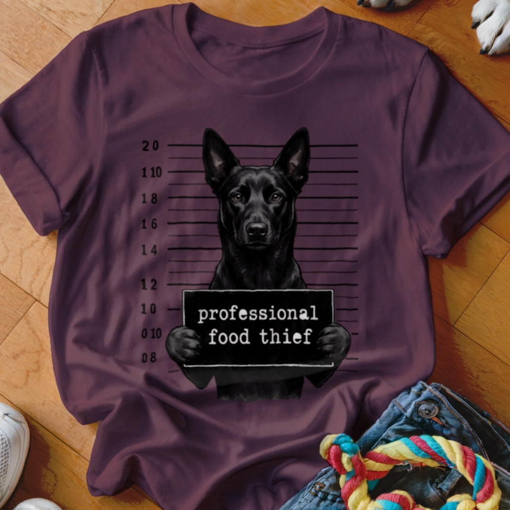 Black dog in mugshot with "professional food thief" sign.