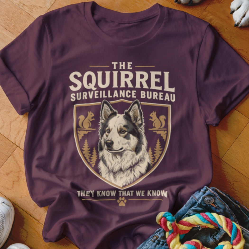 A dark purple t-shirt featuring a crest with a dog and the text The Squirrel Surveillance Bureau.
