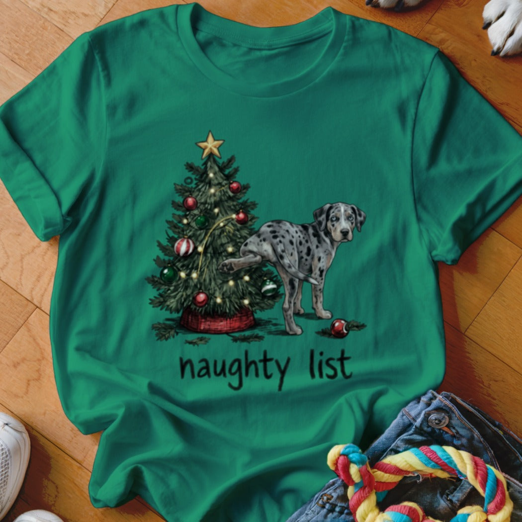 Green t-shirt featuring a spotted dog peeing on a decorated Christmas tree with the text naughty list.