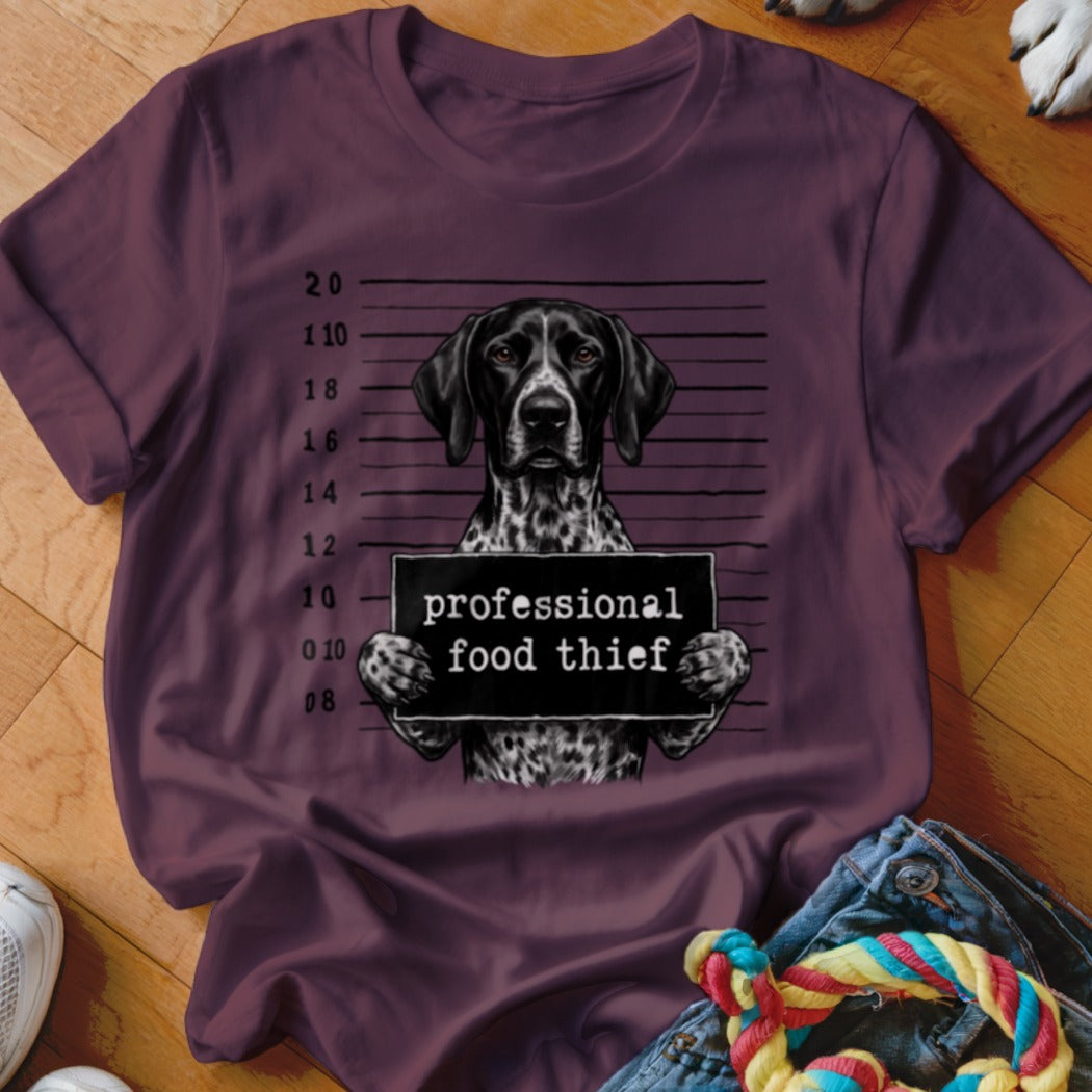 German Shorthaired Pointer in mugshot, holding "professional food thief" sign.