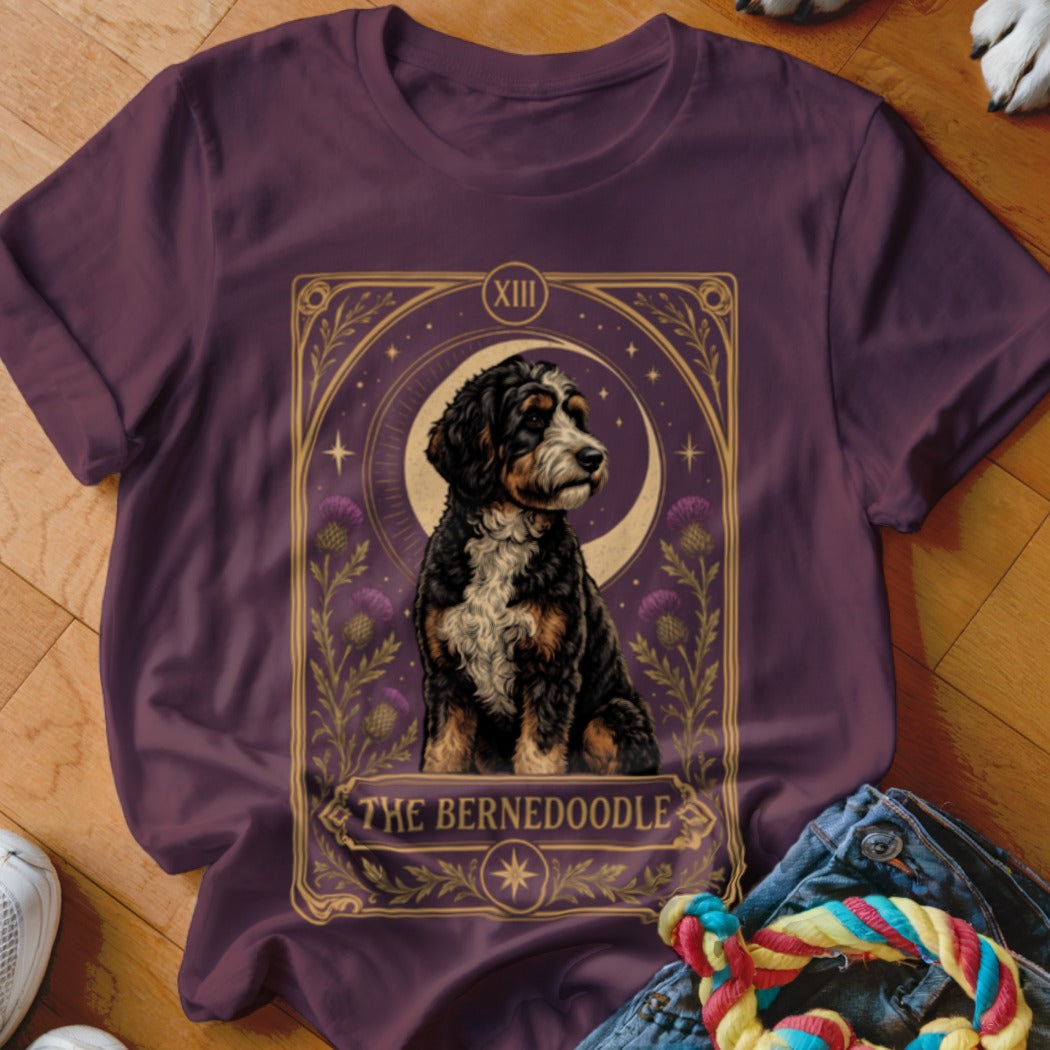 A plum-colored t-shirt displays a tarot-style graphic of a Bernedoodle dog with the text The Bernedoodle.
