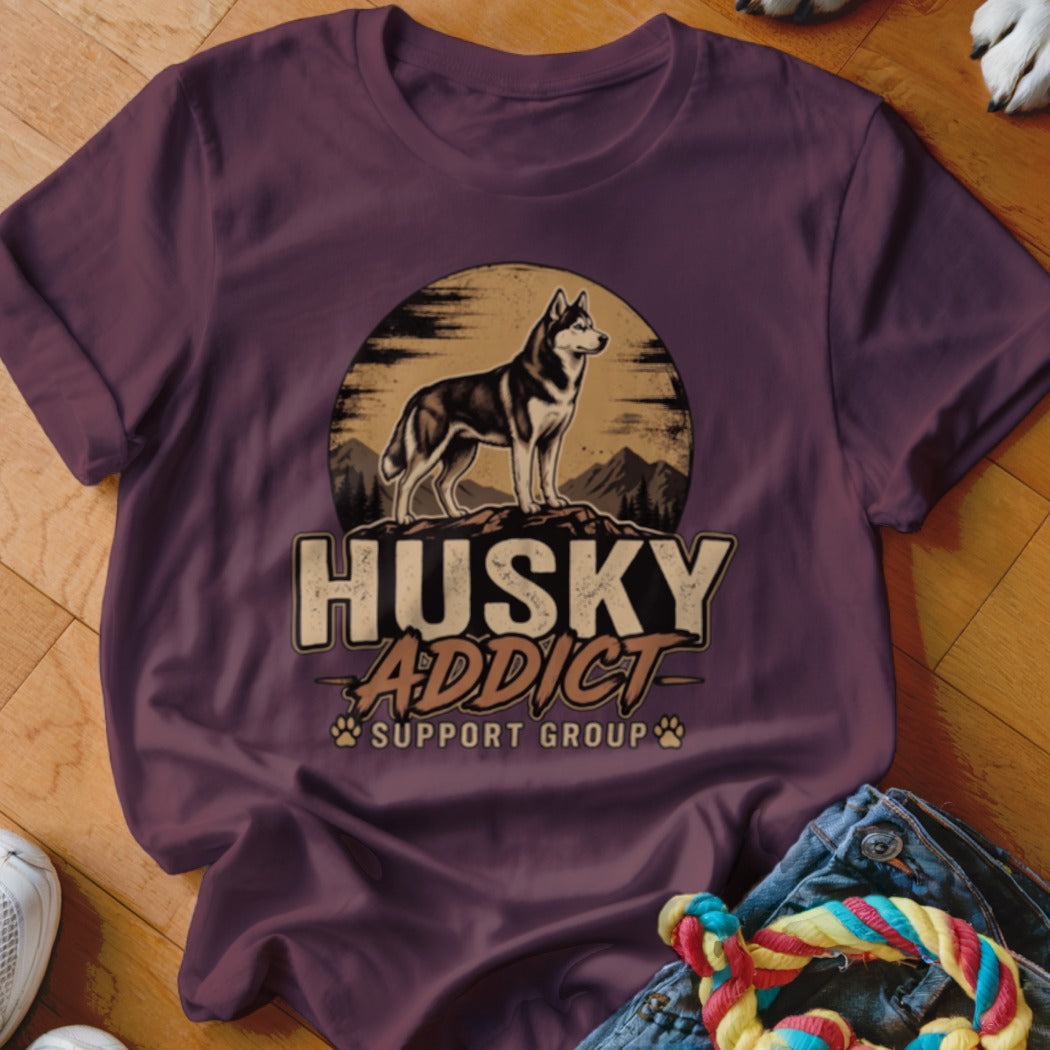 A dark purple t-shirt featuring a graphic of a husky standing on rocks with the text Husky Addict Support Group.