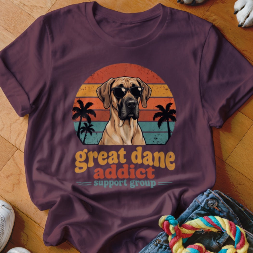 A purple t-shirt featuring a Great Dane wearing sunglasses against a sunset graphic with palm trees and the text Great Dane Addict Support Group.