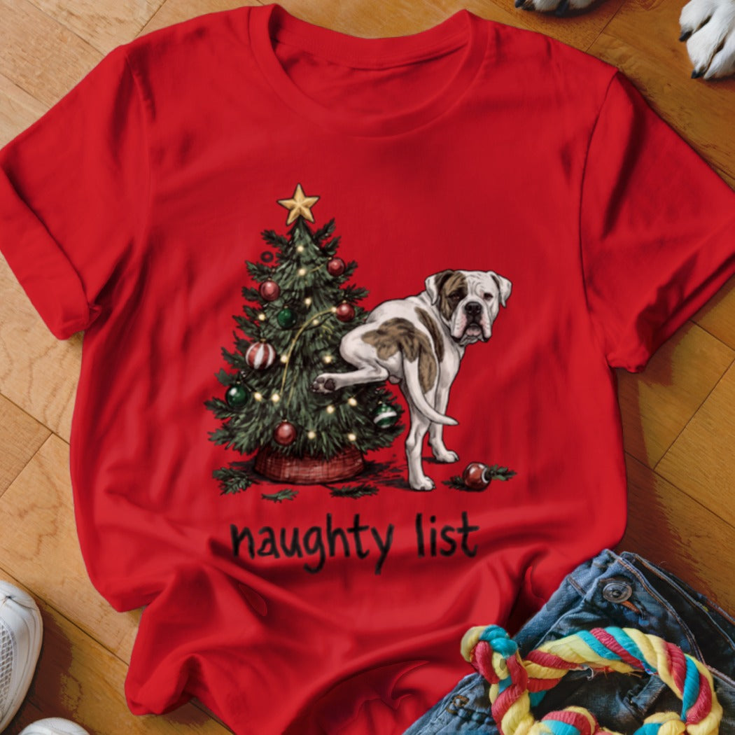 Bulldog near Christmas tree with text "naughty list" on red shirt.