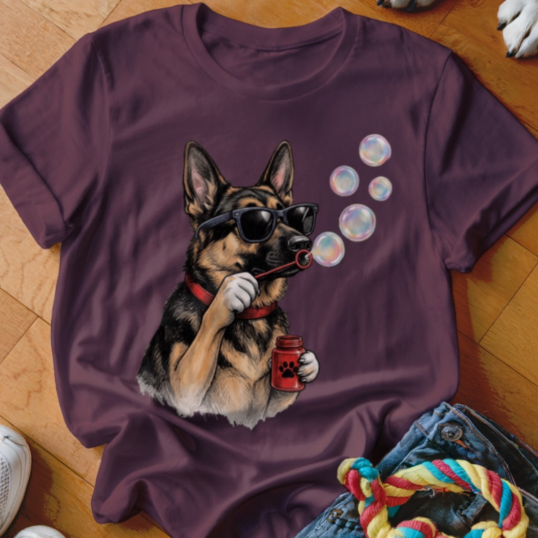 A dark purple t-shirt featuring a graphic of a German Shepherd wearing sunglasses and blowing bubbles.