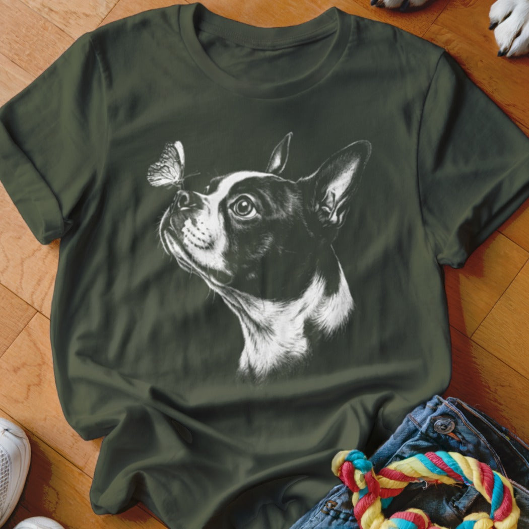 An olive green t-shirt features a white illustration of a Boston terrier with a butterfly on its nose.