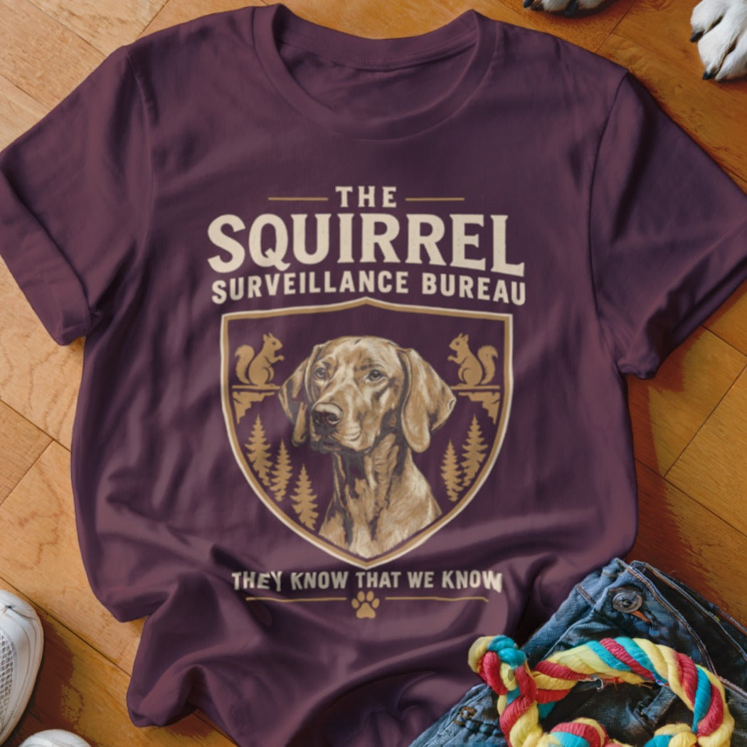 Maroon t-shirt with a graphic of a dog, squirrels, and the text The Squirrel Surveillance Bureau.