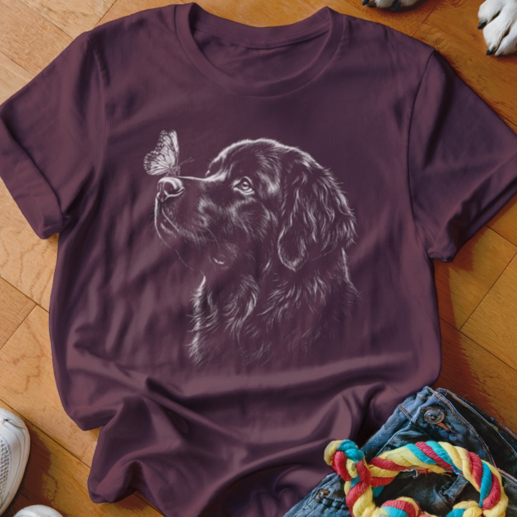 A dark purple t-shirt featuring a white line drawing of a dog looking at a butterfly on its nose.
