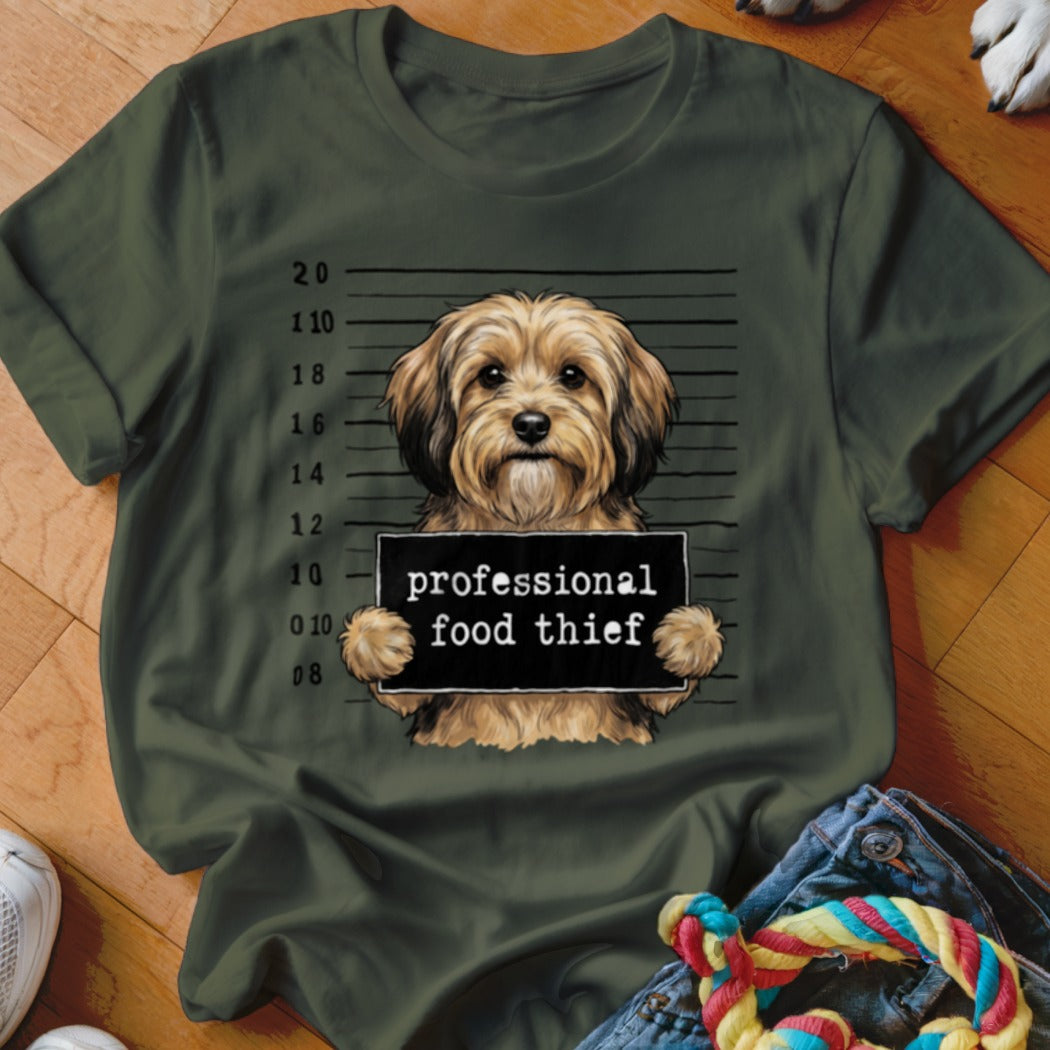 Brown dog holding a sign that says "professional food thief" in front of a mugshot background.