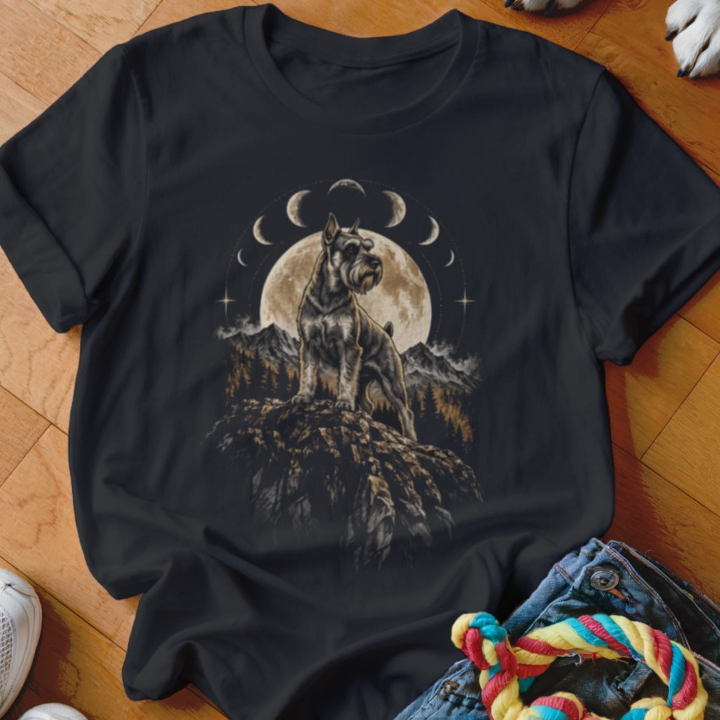 A black t-shirt features a graphic of a Schnauzer standing on a cliff before a full moon and mountain landscape, framed by moon phases.