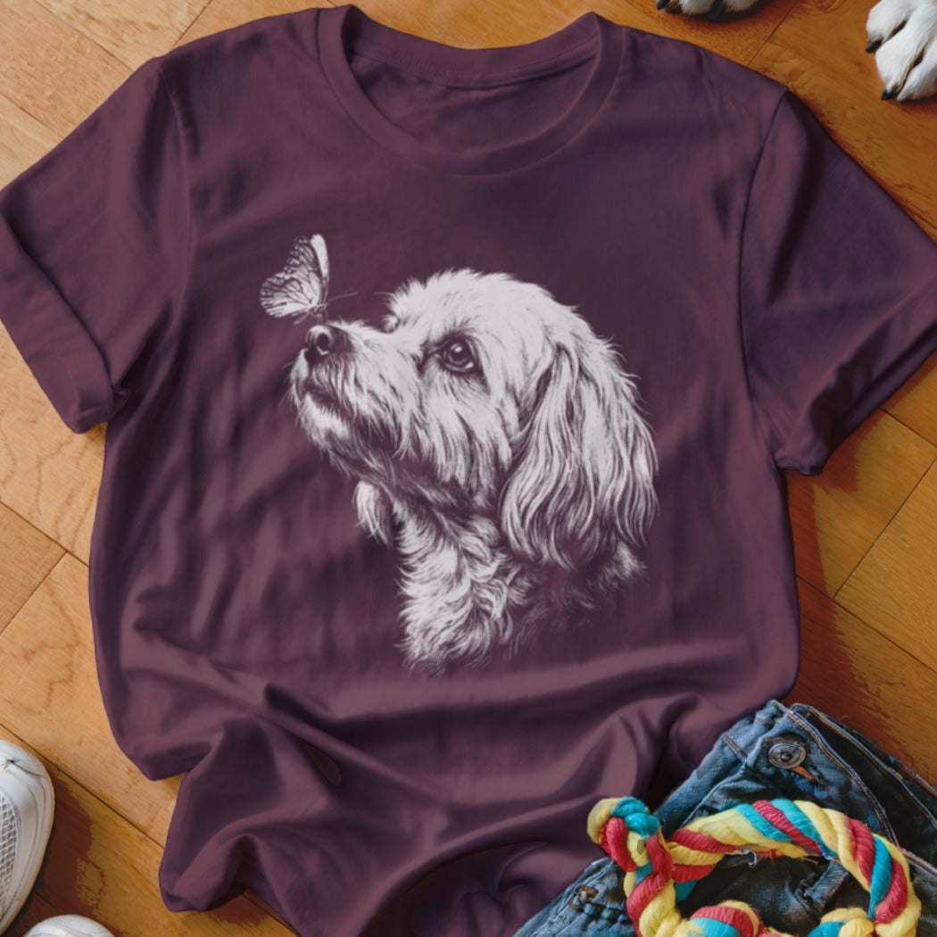 Maroon t-shirt featuring a white sketch graphic of a fluffy dog looking up at a butterfly.