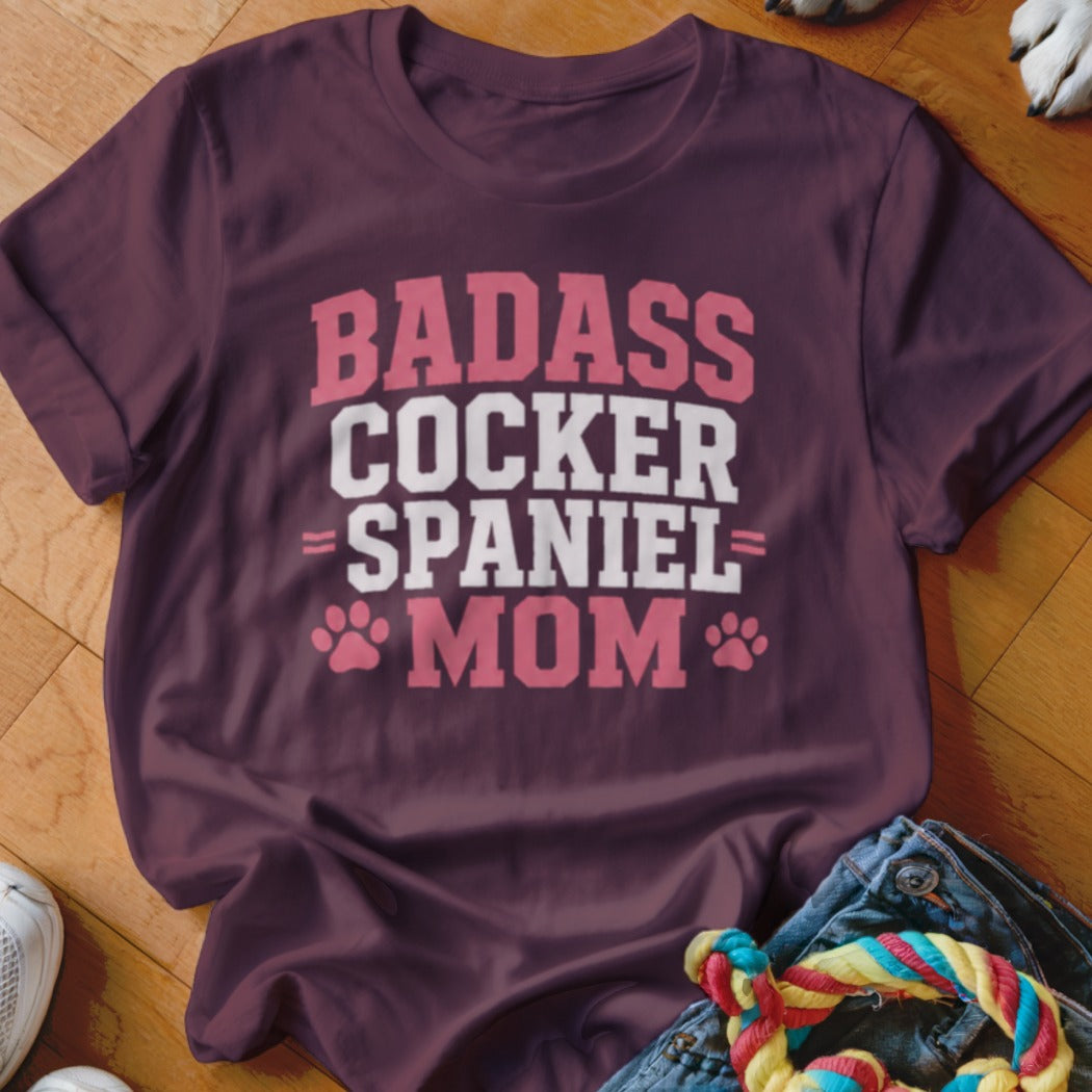 Burgundy t-shirt with "Badass Cocker Spaniel Mom" text and paw prints.