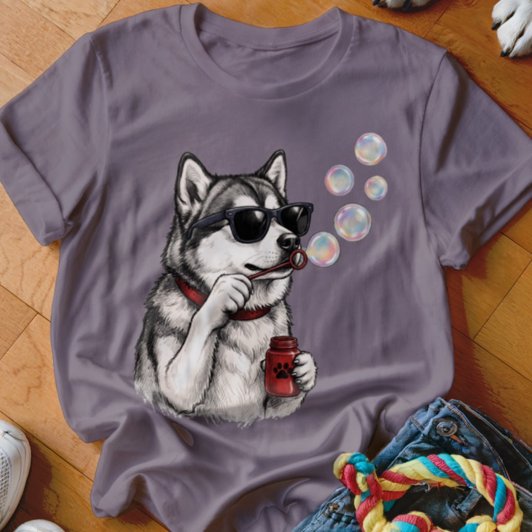 A purple t-shirt featuring a graphic of a husky wearing sunglasses and blowing soap bubbles.