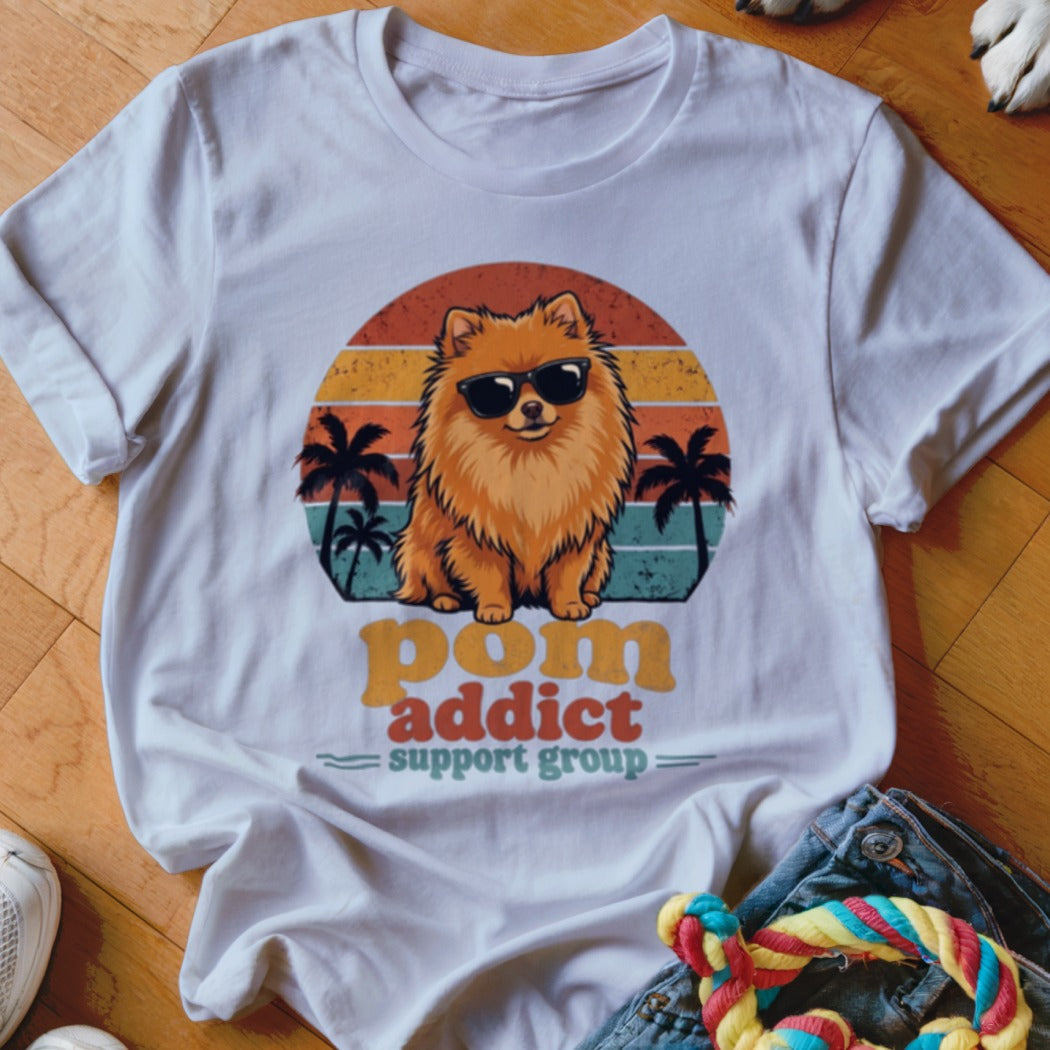 White t-shirt featuring a retro graphic of a Pomeranian wearing sunglasses with sunset and palm trees.