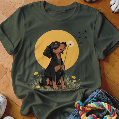 Dark green t-shirt featuring an illustration of a puppy blowing dandelion seeds against a yellow moon.