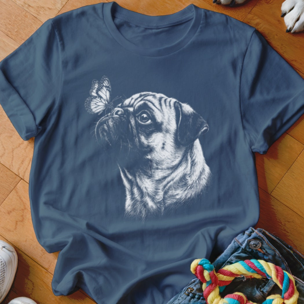 A dark blue t-shirt printed with a white sketch of a pug looking at a butterfly.