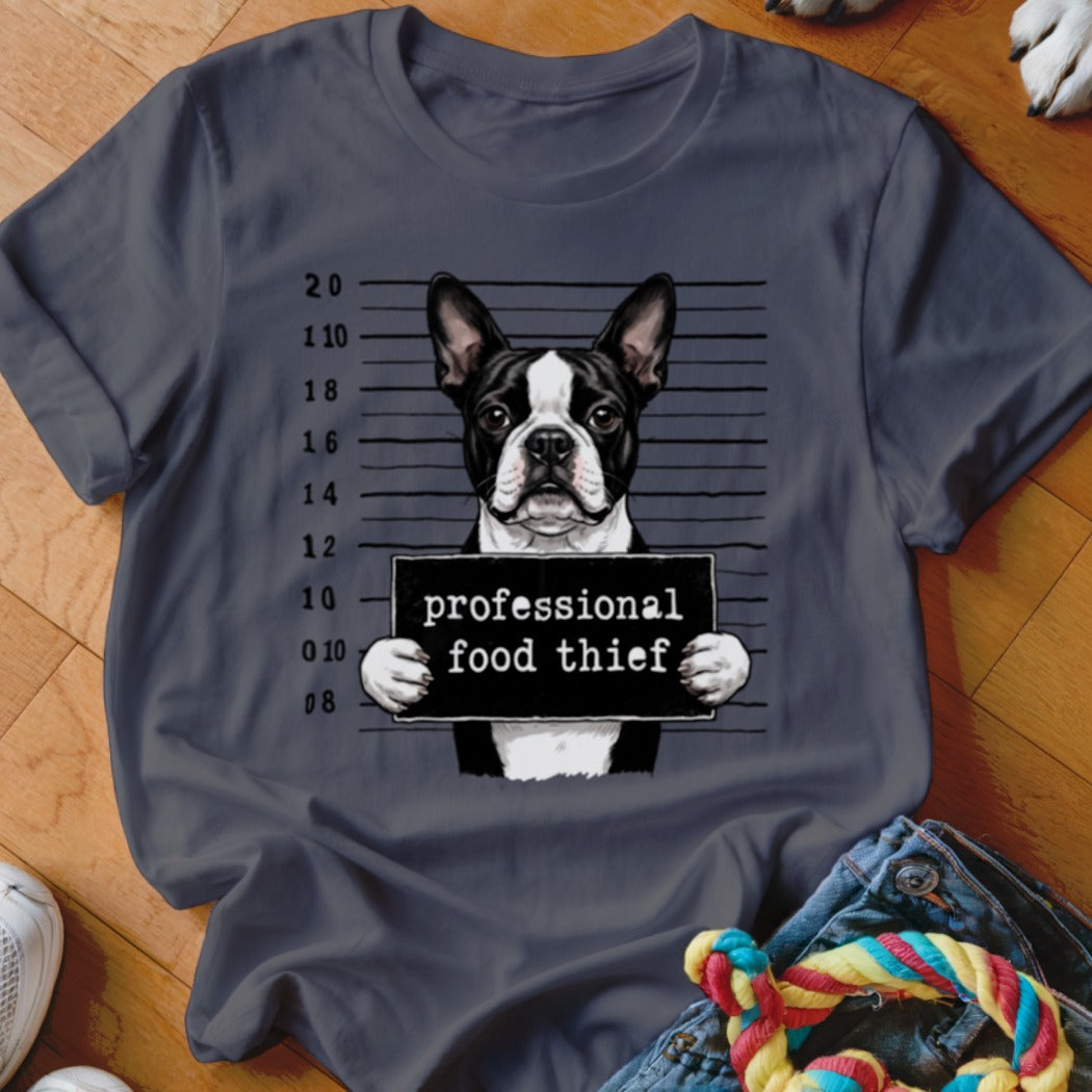 Boston Terrier mugshot with "professional food thief" sign on a dark grey t-shirt.