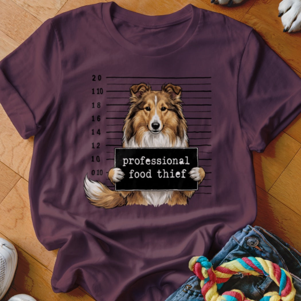 Sheltie dog mugshot with "professional food thief" sign.
