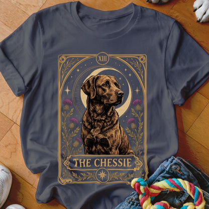 A dark grey t-shirt featuring a tarot card design of a brown dog with text reading THE CHESSIE.
