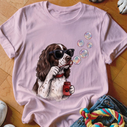 Light pink t-shirt featuring an illustration of a brown and white spaniel wearing sunglasses and blowing bubbles.