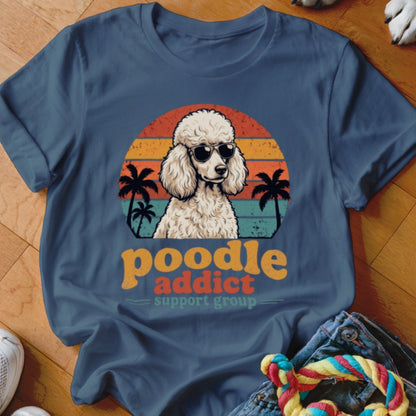 A slate-blue t-shirt featuring a retro graphic of a poodle in sunglasses with palm trees and sunset stripes.