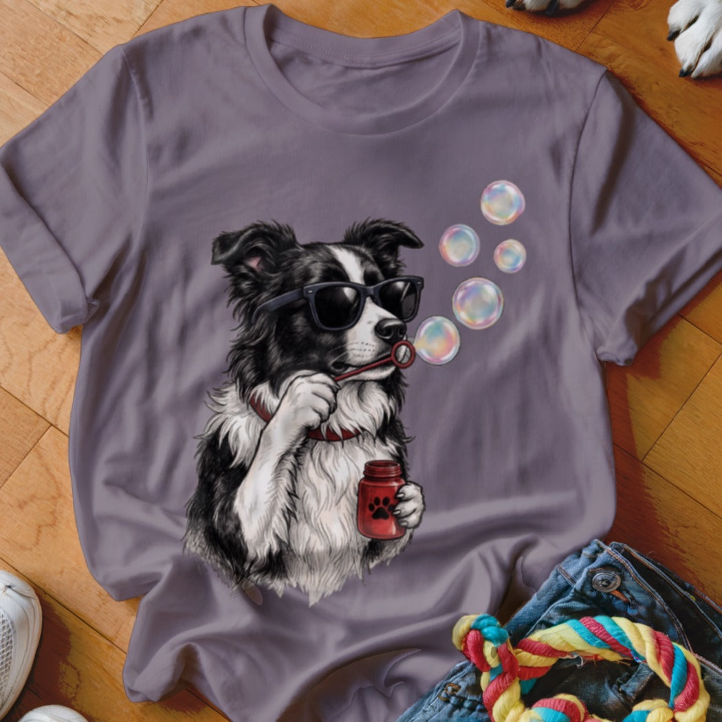 A grey t-shirt featuring an illustration of a Border Collie wearing sunglasses and blowing bubbles.