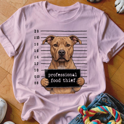 Pit bull mugshot with sign reading "professional food thief" on pink t-shirt.