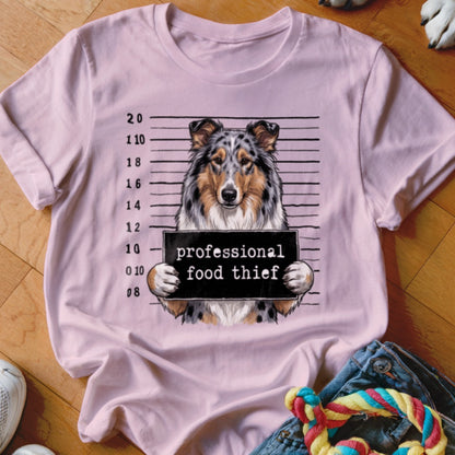 Dog mugshot with "professional food thief" sign on a light pink t-shirt.