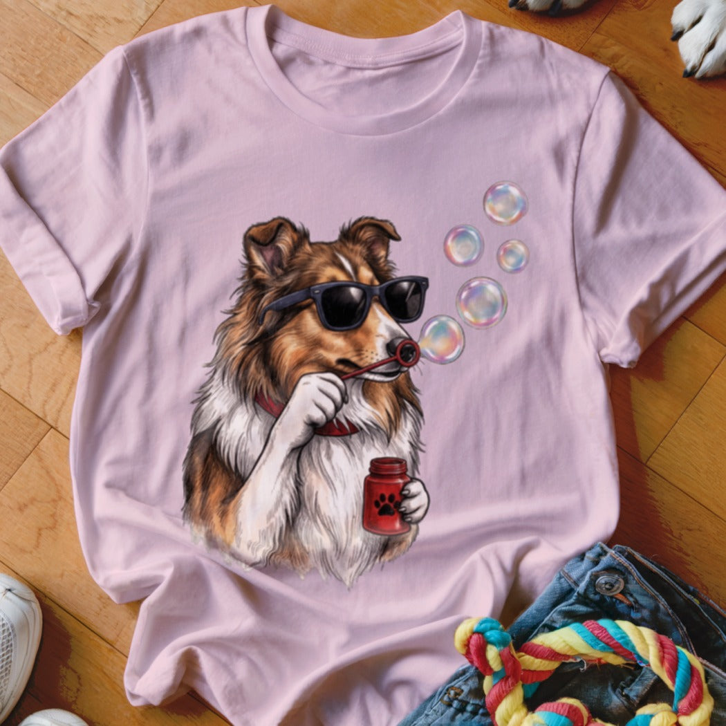 Light pink t-shirt featuring a graphic of a Sheltie dog wearing sunglasses and blowing bubbles.
