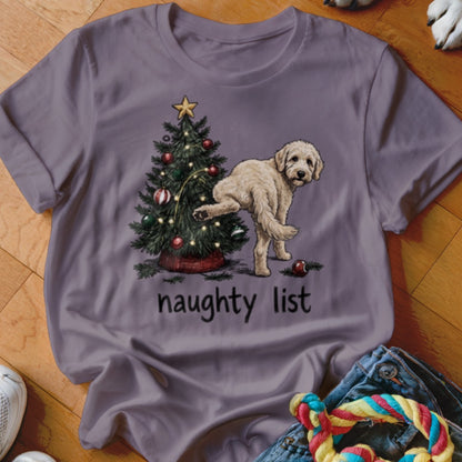 Light-colored dog lifting leg next to decorated Christmas tree with "naughty list" text.