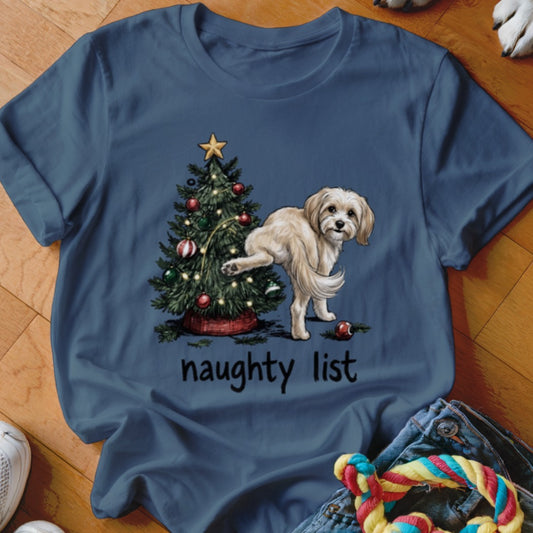 Dog near Christmas tree with text "naughty list" on blue shirt.