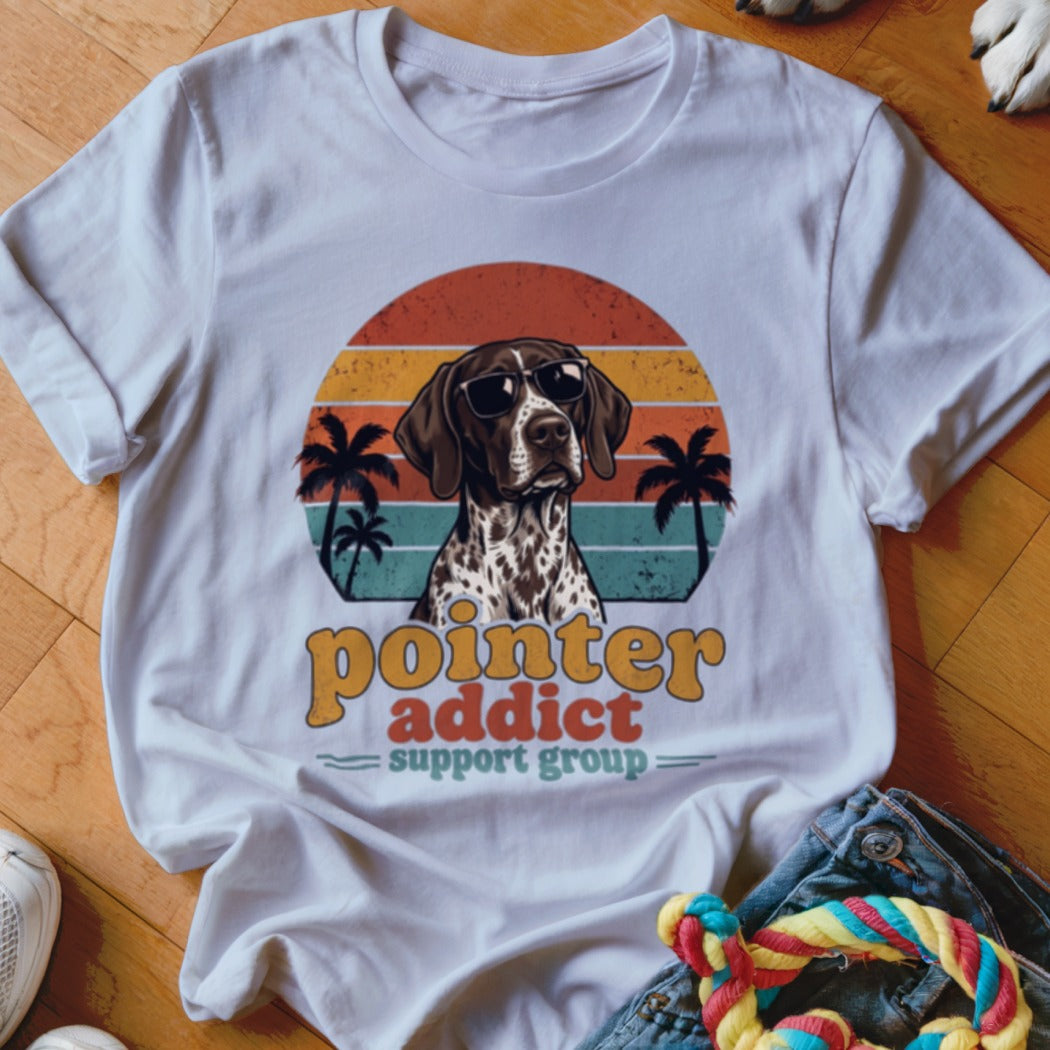 A white t-shirt featuring a graphic of a German Shorthaired Pointer wearing sunglasses against a retro sunset and palm tree background, with the text "pointer addict support group".
