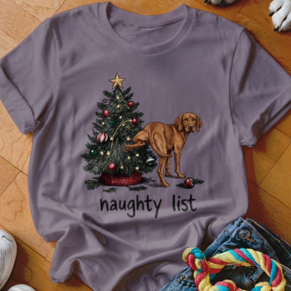 A purple t-shirt featuring a graphic of a brown dog urinating on a Christmas tree with the text naughty list.
