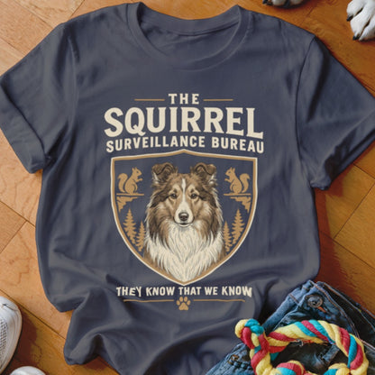 A dark gray t-shirt featuring a graphic of a Sheltie dog and the text The Squirrel Surveillance Bureau.