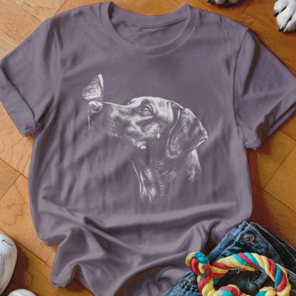 A purple short-sleeved t-shirt featuring a white line drawing of a dog looking at a butterfly.