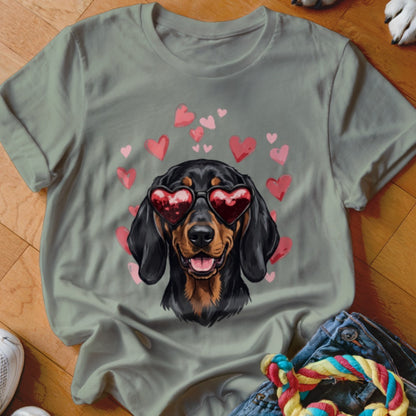 Sage green t-shirt featuring a graphic of a dachshund wearing heart-shaped sunglasses, surrounded by pink hearts.