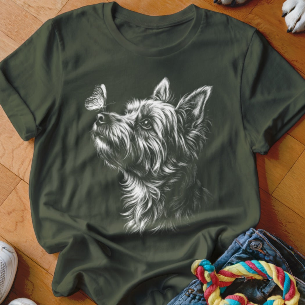 A dark green crewneck t-shirt featuring a white sketch of a terrier looking at a butterfly on its nose.