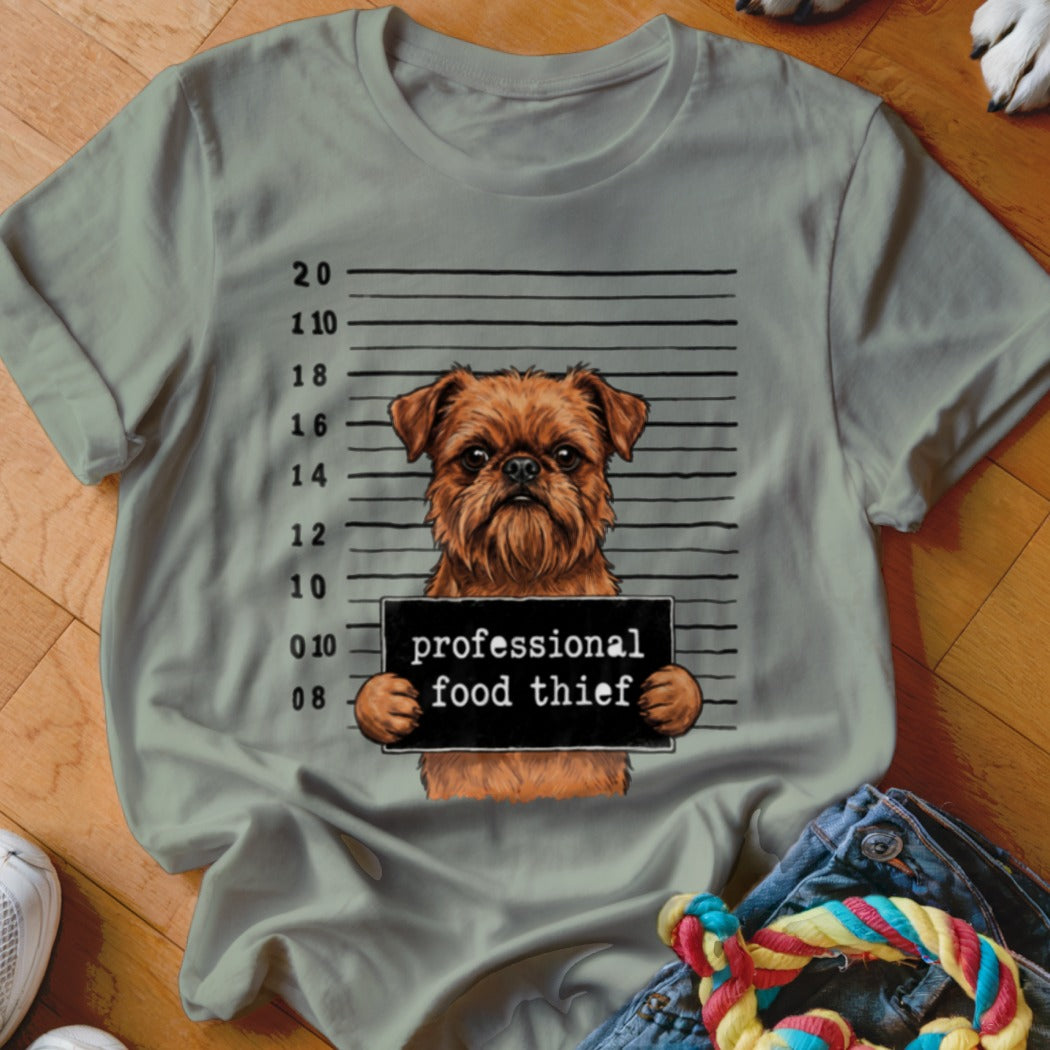 Brown dog in mugshot holding sign "professional food thief"