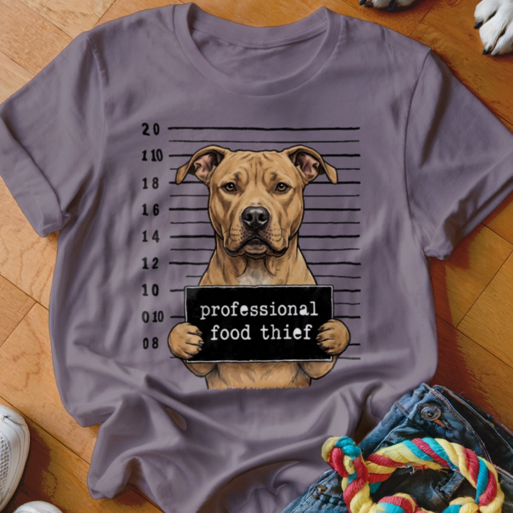 Dog wearing a sign that says "professional food thief" in a mugshot.
