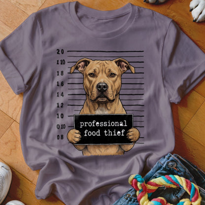 Dog wearing a sign that says "professional food thief" in a mugshot.