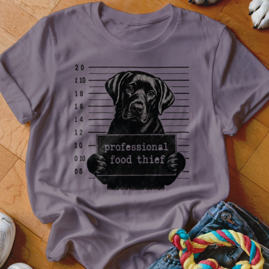 Black lab mugshot with sign reading "professional food thief".