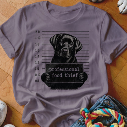 Black lab mugshot with sign reading "professional food thief".