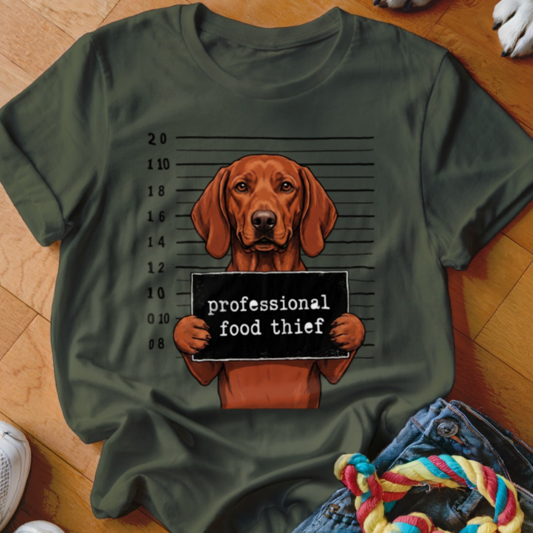 T-shirt graphic of a dog in a mugshot holding a "professional food thief" sign.