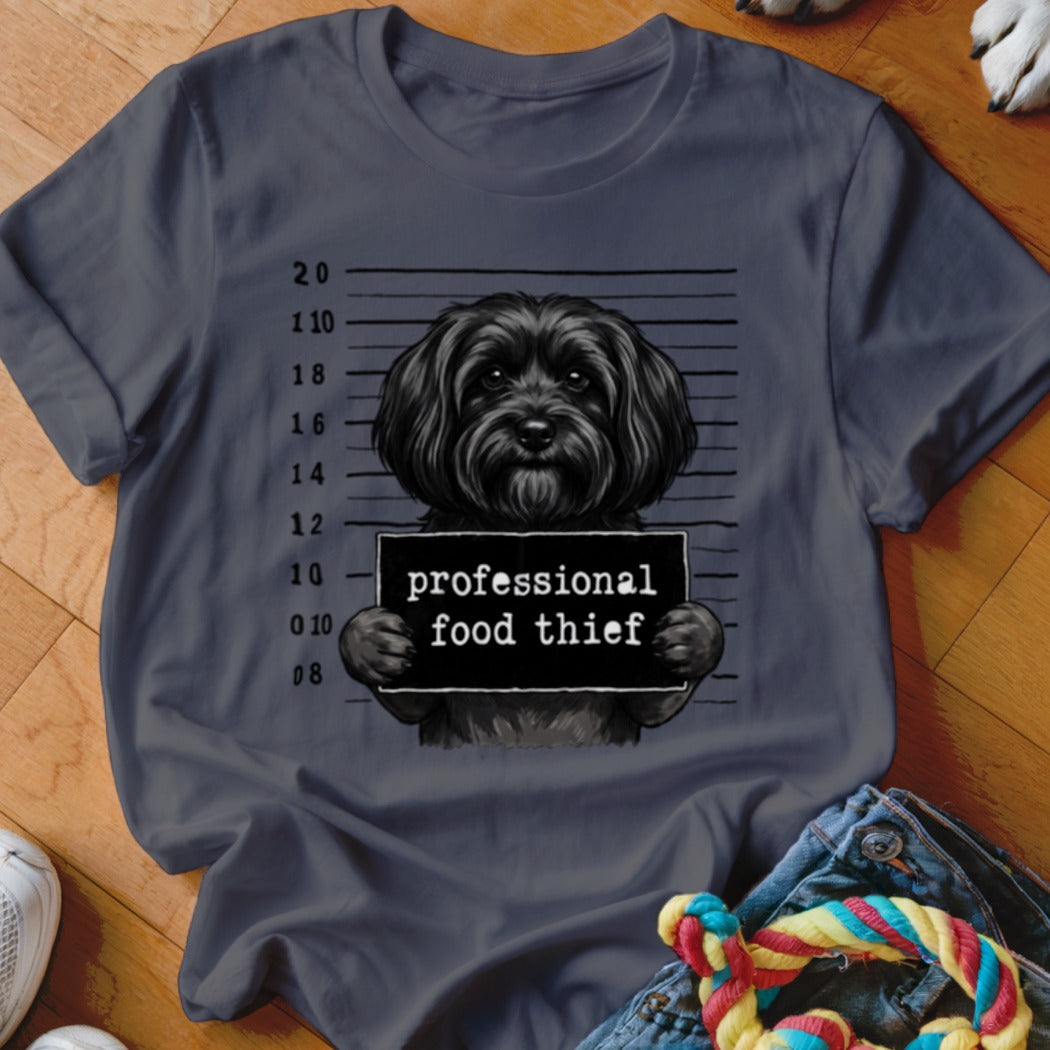 Black dog mugshot with sign saying "professional food thief".