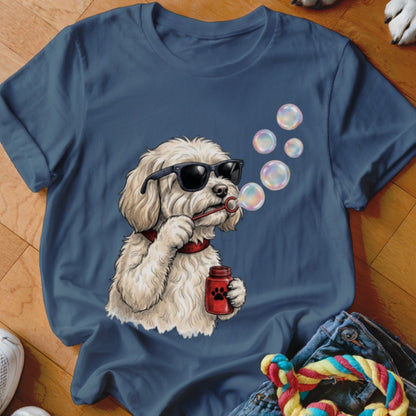 Blue t-shirt featuring an illustration of a fluffy white dog wearing sunglasses and blowing bubbles.